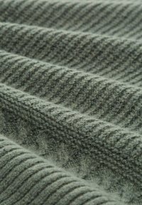 Dzianina w stonowanej zieleni, z teksturowanym wzorem z wypukłymi prążkami i subtelnymi różnicami w grubości. Miękki, ciepły wygląd.