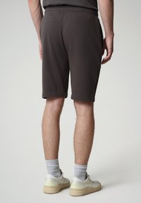 Shorts in cotone jersey grigio carbone con tasche laterali, vita elastica e orlo arrotolato, abbinati a sneaker bianche e calzini grigi.