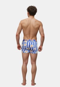Blå og hvide stribede boxer shorts med æggemønstre og en orange "MR KO" elastik i taljen. Materialet ser strækbart og tætsiddende ud. Ingen andre detaljer.