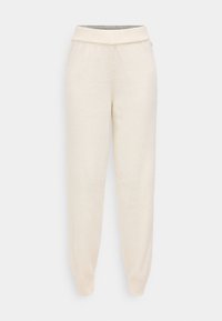 Pantalones jogger de color crema con tejido texturizado, cintura elástica y puños acanalados. Diseño simple, sin patrones ni acentos visibles.