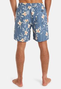 Modré plavky s kvetinovým vzorom, ktorý má žlté kvety s červenými akcentmi. Vyrobené z ľahkého materiálu s voľným strihom.