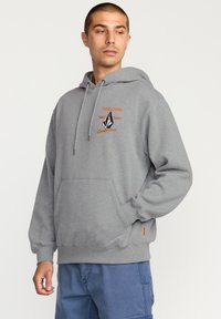 Grijze fleece hoodie met trekkoord, voorzak en oranje logo-detailing. Voorzien van ribgebreide manchetten en zoom voor een goede pasvorm.