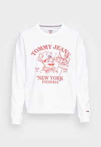 Felpa bianca con collo a giro, caratterizzata da una grafica rossa di un chef e testo "TOMMY JEANS NEW YORK PIZZERIA" in lettere maiuscole.