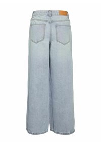 Jean large bleu clair avec poches arrière et une étiquette de marque en cuir marron sur la ceinture.