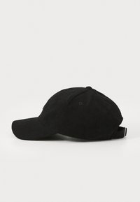 Svart kordfløyelslue med buet skjerm, teksturert stoff, justerbar stropp bak og seks ventilasjonsøyer på kronen.