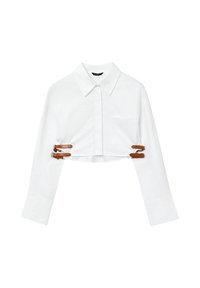 Chemise blanche coupée avec un col pointu, des manches longues, une poche avant et des accents en cuir marron avec boucle pour un ajustement réglable.