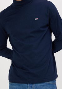 Marineblaue Langarmpoloshirt mit Rollkragen aus glattem Stoff; verfügt über ein kleines gesticktes Logo auf der Brust und hat eine klassische Passform.