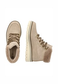 Bottines en suède beige avec un col en fausse fourrure, des accessoires dorés et des lacets marron. Semelle épaisse blanche avec un motif texturé pour une meilleure adhérence.