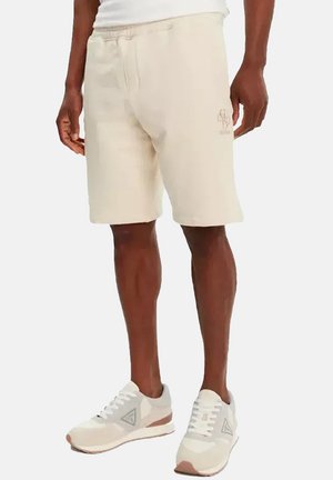 Pantaloni sportivi beige in cotone con vita elastica, dotati di tasche laterali e logo ricamato davanti.