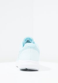 Světle modrá sportovní bota s texturovaným síťovaným svrškem a hladkými syntetickými akcenty; bílá mezipodešev; zaoblený podpatek; minimální viditelnost loga.