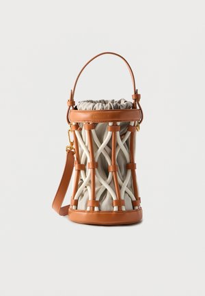 Μικρή κυλινδρική τσάντα από μπεζ ύφασμα, περικλειόμενη σε ένα διασταυρούμενο κλουβί από ταμπά δέρμα, με ταίριαστο δερμάτινο χερούλι και λουράκι.