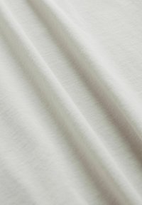 Tessuto di cotone bianco con una superficie liscia, caratterizzato da pieghe morbide e leggermente drappeggiate e da un motivo di tessitura uniforme e costante.