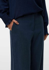 Marinblå byxor i texturerad tyg, med klassisk passform, sidfickor och en slät, polerad yta för en skräddarsydd look.