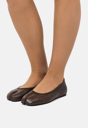Zapatos planos de ballet marrones hechos de cuero suave, con un diseño distintivo de separación en los dedos, punta redondeada y suela plana.