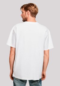 White cotton T-shirt with a relaxed fit, short sleeves, and a crew neckline, shown from the back, paired with light blue jeans.