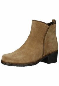 Botte cheville en daim marron clair avec un bout arrondi et un petit talon bruit, dotée de détails cousus et d'un col légèrement relevé.