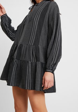 Schwarz-weiß gemustertes Kleid mit langen Ärmeln, Peplum-Design, mit einem knopfbeschlossenen Schlüsselloch-Ausschnitt und strukturiertem Stoff.