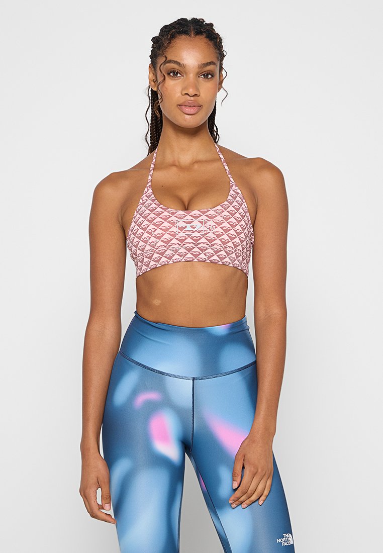 Soutien-gorge de sport en rose avec un motif de losanges matelassés, associé à un legging bleu avec des accents abstraits en rose et violet. Finition en tissu lisse.