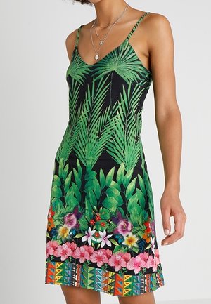 Sundress with green leaf print on black background, featuring floral accents and geometric patterns at the hem. Spaghetti straps, knee-length.