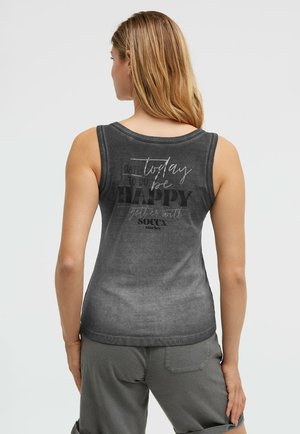 Woman with long hair wearing a faded black sleeveless top with the text "today to do: be happy" on the back and gray shorts.
