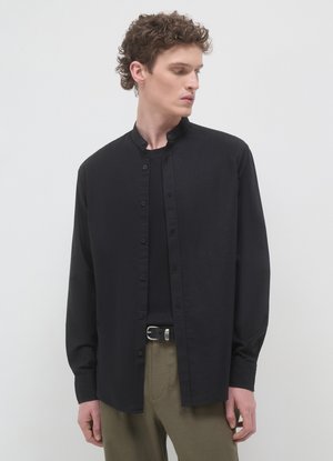 Chemise noire à boutons avec un col mandarin, fabriquée en tissu léger. Présente des manches longues et une coupe droite.