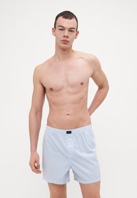 Modre in bele črtaste bokserice z elastikom v pasu, z enim gumbom za zapiranje in mehkim bombažnim materialom.