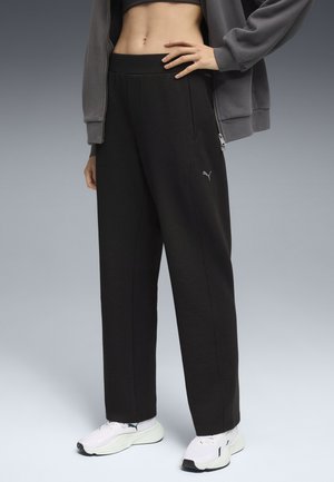 Black sweatpants with a relaxed fit, featuring front pockets and a soft texture. A small gray Puma logo is visible on the left thigh.