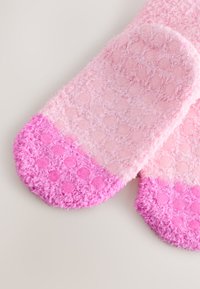 Miękkie, różowe skarpetki z teksturowanymi kropkami i jednolitym, ciemnoróżowym noskiem. Wykonane z puszystego materiału, o gładkim, wyściełanym fasonie.
