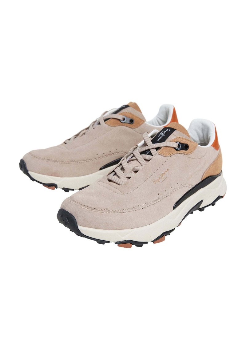 Zapatillas de ante color arena con una suela acolchada color crema, acentos marrones en contraste, cordones negros y una suela de goma texturizada. Diseño elegante y contemporáneo.