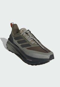 Men's athletic shoe in olive green and grey. Features breathable mesh upper, three black stripes, and thick outsole with "LIGHT BOOST" detail.