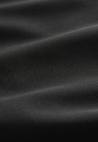 Tissu noir texturé présentant un léger éclat, avec un drapé lisse et un motif de tissage uniforme tout au long.