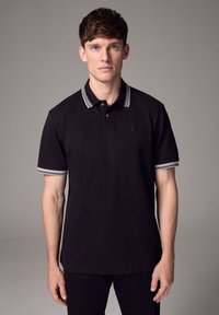 Fekete póló ing, két gombos gallérral, szürke csíkkal a gallér és az ujjak szegélyén; sima, légies anyagból készült.