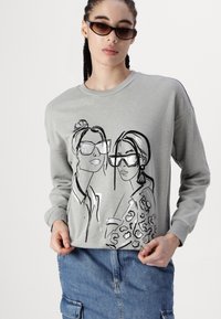 Szürke pulóver, amelyen két nő grafikus designja látható. Simább anyag, kerek nyakkivágás és hosszú ujjú. A farmer szoknya teszi teljessé a megjelenést.