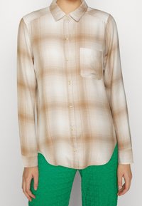 Camicia a maniche lunghe a quadri beige e bianca con colletto button-down e taschino singolo, realizzata in tessuto leggero.