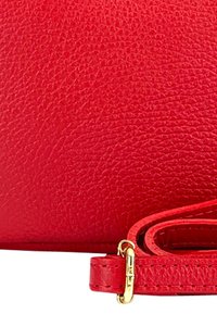 Rode leren schoudertas met een gestructureerd oppervlak, voorzien van een gouden sluiting en een dunne, verstelbare schouderband.