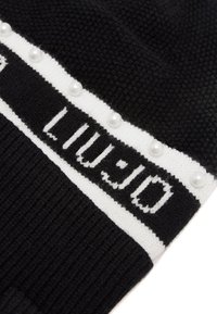 Beanie lavorato a maglia nero con una fascia bianca con la scritta "LIU-JO" e perle decorative bianche lungo il bordo superiore. Superficie testurizzata.