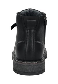 Schwarze Lederstiefelette mit seitlichem Reißverschluss, genähten Details, einer Zuglasche an der Ferse und einer strukturierten Gummisohle, von hinten betrachtet.