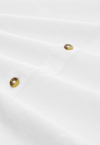 Witte shirt met een gladde textuur, twee ronde bruine knopen, subtiele stikdetails en een gevouwen ontwerp.