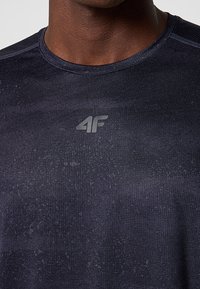 Granatowa koszulka sportowa wykonana z tkaniny odprowadzającej wilgoć, z okrągłym dekoltem i delikatnym wzorem teksturowym oraz nadrukowanym logo.