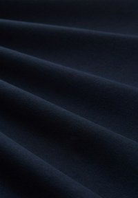 Ciemnoniebieska tkanina o gładkiej fakturze, prezentująca miękkie, płynące fałdy i subtelny połysk na swojej powierzchni.