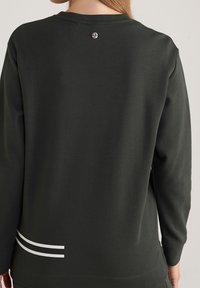 Tmavozelená mikina s dlouhými rukávy, která má kruhový detail u krku a bílé proužky v dolní části zad. Hladká textura.