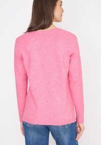 Fuchsia-pinker Pullover mit langen Ärmeln, einem runden Halsausschnitt und gerippten Bündchen. Weicher Stoff mit einem dezenten melierten Muster.