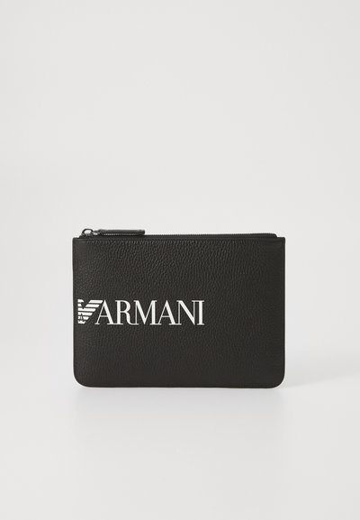 Crni kožni mjehur s teksturiranom površinom, s bijelim logotipom "ARMANI" i zatvaranjem na patentni zatvarač na vrhu. Pravokutnog oblika.