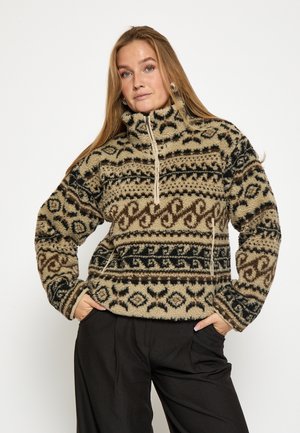 Fleece-pusero korkealla kauluksella, jossa on mustan, ruskean ja beigeen sekoittuvia kuvioita. Pehmeä pinta ja edessä vetoketjukiinnitys; kaksi sivutaskua.