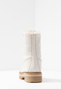 Bota blanca impermeable con un acabado texturizado, forro de piel sintética en la parte superior y suela de goma. Presenta costuras y detalles en dorado.