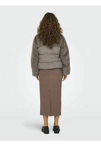 Gray padded jacket with a fuzzy texture, styled over a brown midi skirt with a back slit, paired with black platform shoes.