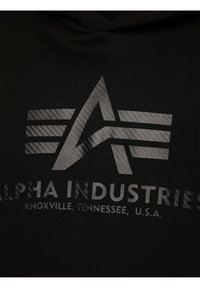Zwarte hoodie met een grijze afbeelding van een "A" met drie strepen erboven en de tekst "ALPHA INDUSTRIES, KNOXVILLE, TENNESSEE, U.S.A."