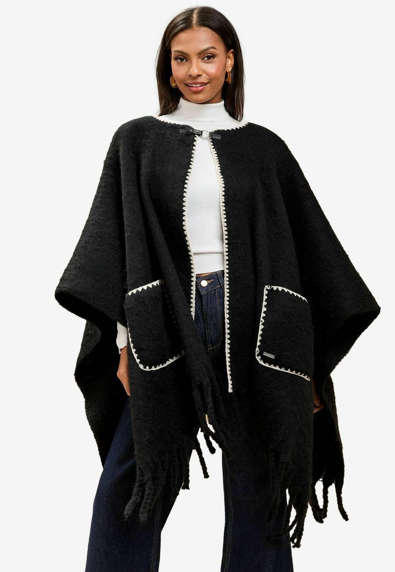 Poncho nero in lana con collo rotondo, bordatura bianca, due tasche frontali e dettagli con frange lungo l'orlo. Design morbido e ampio.
