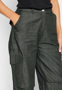 Spodnie cargo w ciemnoszarym materiale, charakteryzujące się luźnym krojem, bocznymi kieszeniami i subtelnym wzorem teksturowanym, z zapięciem na guzik z przodu.