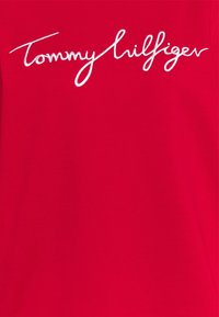Rode T-shirt met wit geborduurd "Tommy Hilfiger" logo. Glad katoen, korte mouwen en ronde halslijn. Eenvoudig ontwerp.